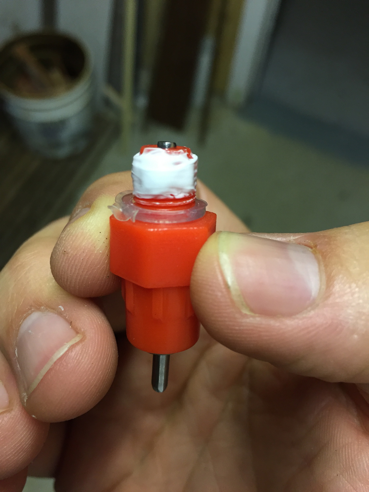 A chicken nipple with silicone sealant around the thread, ready to screwed into the bottom of the bucket.