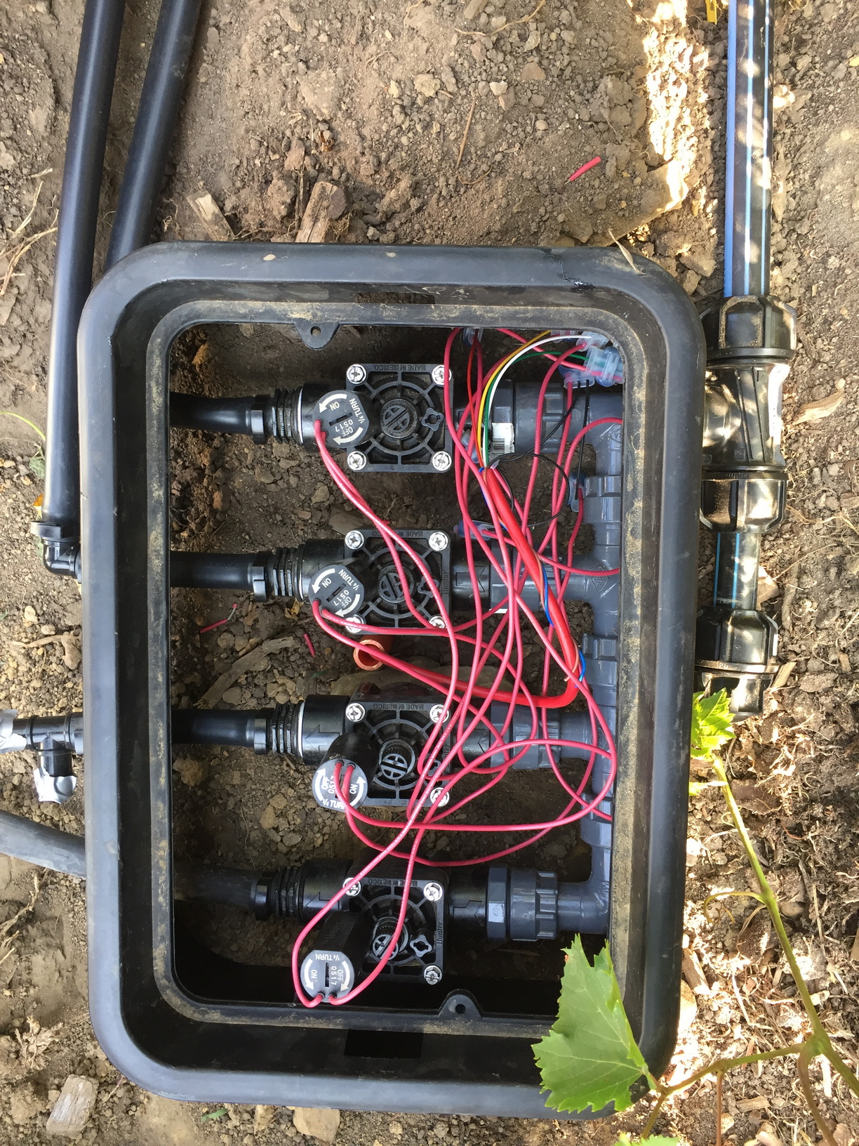 Solenoid valve box fully loaded with 4 valve manifold and connected to low-density 19mm poly-pipe. The supply from the rainwater tanks has an end-cap installed on the other side of the T connector.