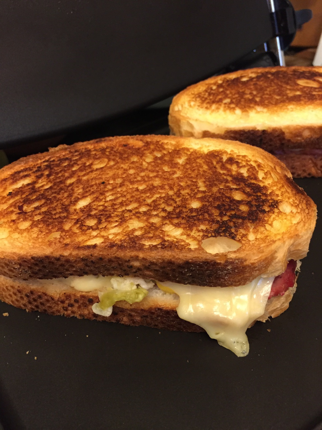 A freshly toasted Reuben, with Swiss cheese melting out of the side